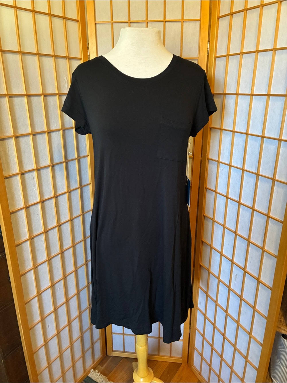 Women’s knee length black t-shirt dress with breast pocket.